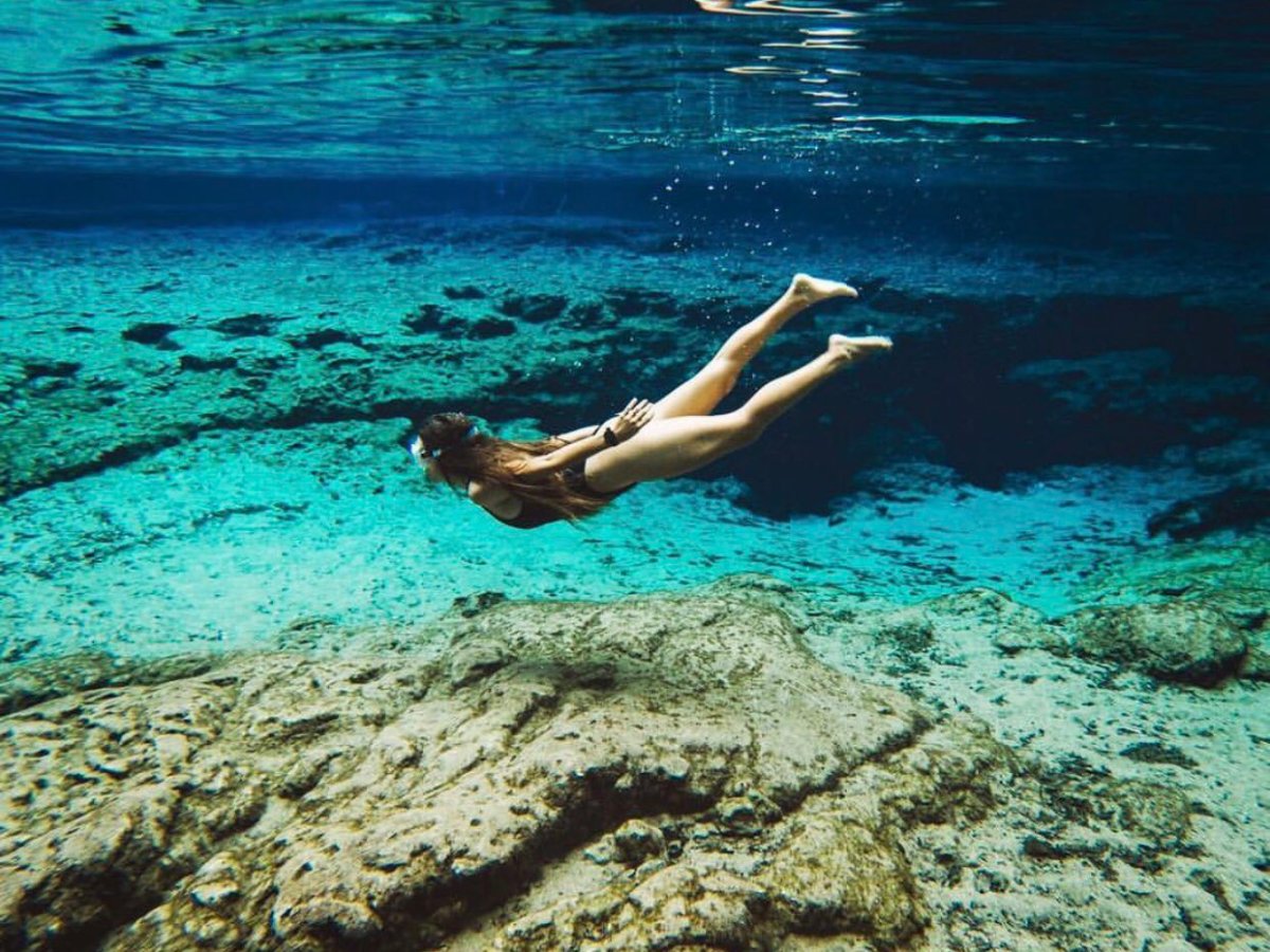 a person sitting on a rock in the middle of a body of water